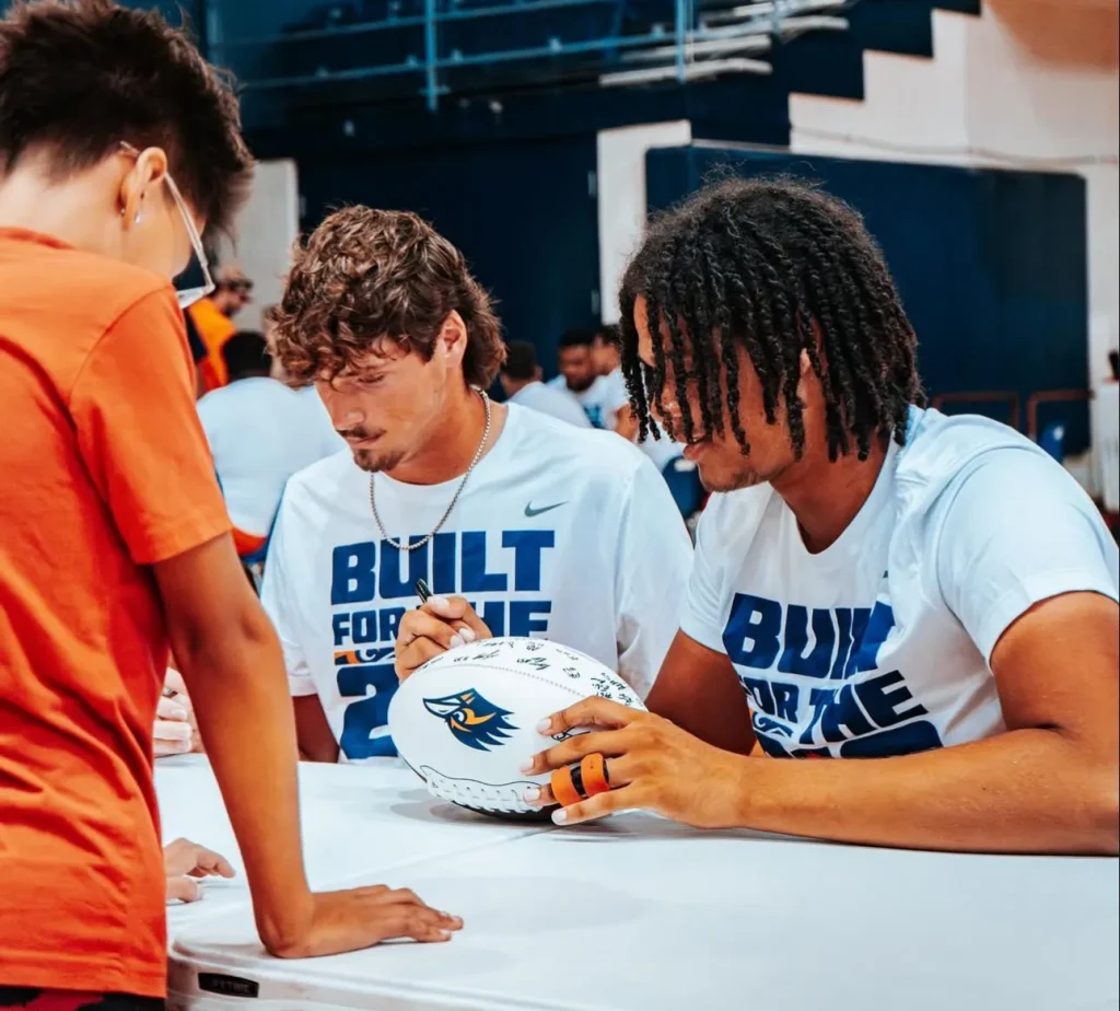 Isaiah Butler-Tanner signing a football at UTSA event